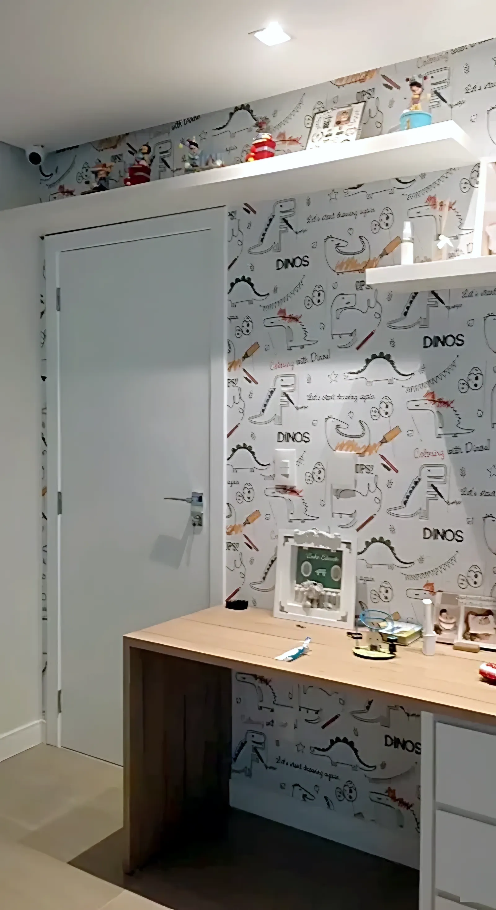 Papel de parede com desenhos de dinossauros em quarto infantil com escrivaninha, em Feira de Santana